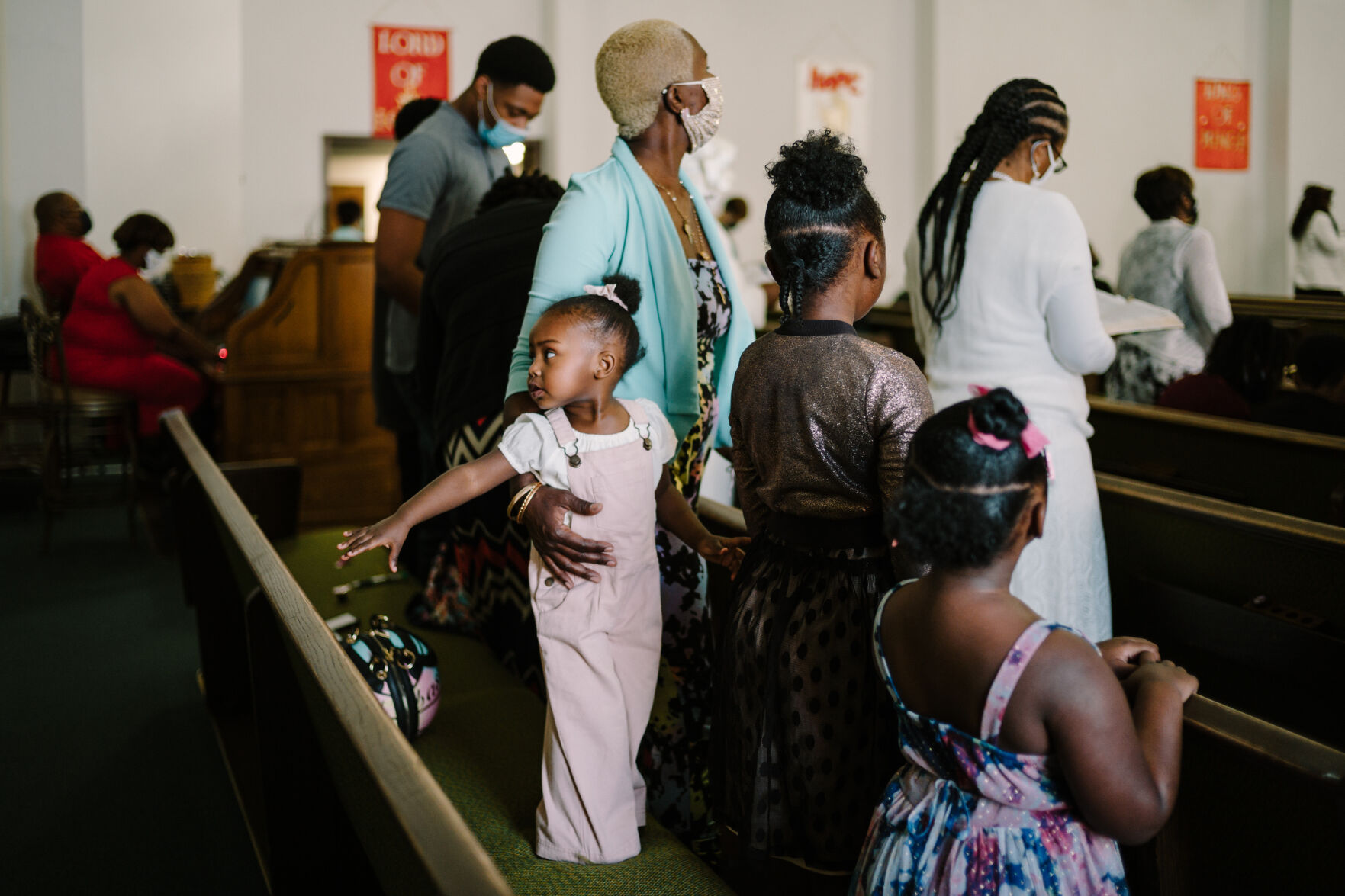 Legacy Jordan, 1, reaches toward another member of the congregatio